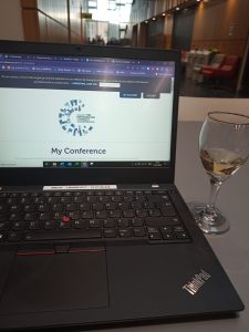 laptop showing LILAC screen and a glass of white wine to the right of the laptop.
