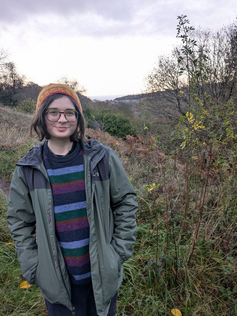 Niamh Kelly stands outside in a jumper and hat